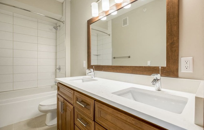 Dual sinks in bathroom with tiled tub in premium unit at Ascend at Woodbury new luxury apartments in Woodbury MN 55129