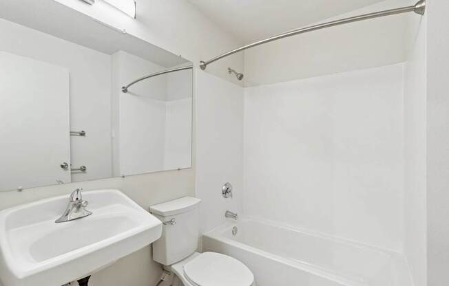 A white bathroom with a toilet, sink, and bathtub.