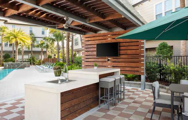 A patio with a bar and chairs under a roof.