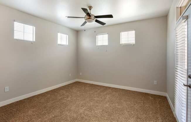a bedroom with a ceiling fan and three windows