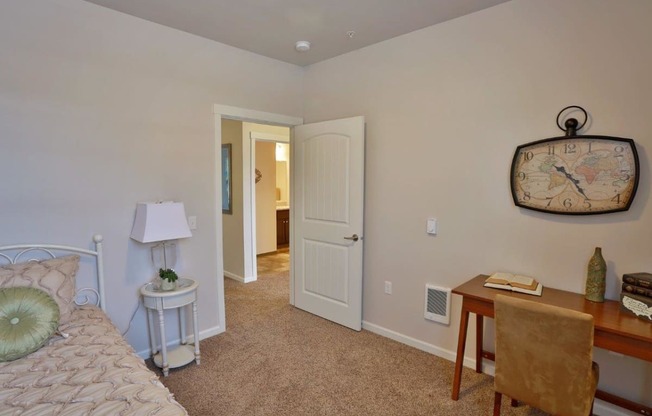 a bedroom with a bed and a desk with a clock