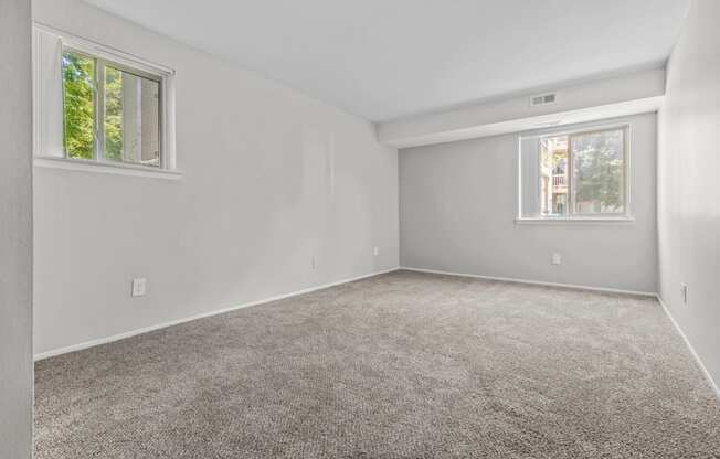 an empty bedroom with carpet and two windows