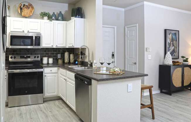 A kitchen with white cabinets and a black countertop.
