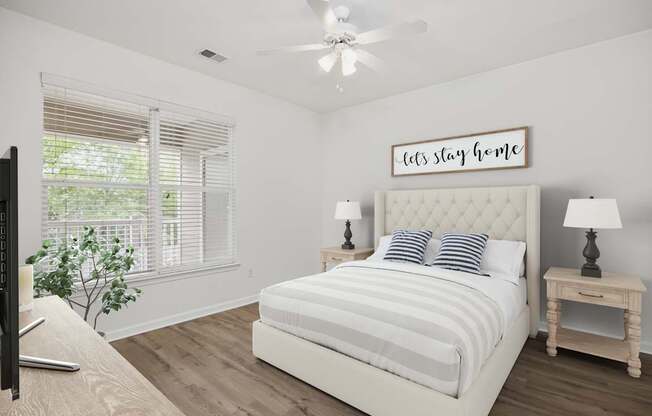 A bedroom with a bed, a ceiling fan, and a window with blinds.