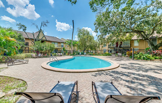 a backyard with a pool and patio with chairs