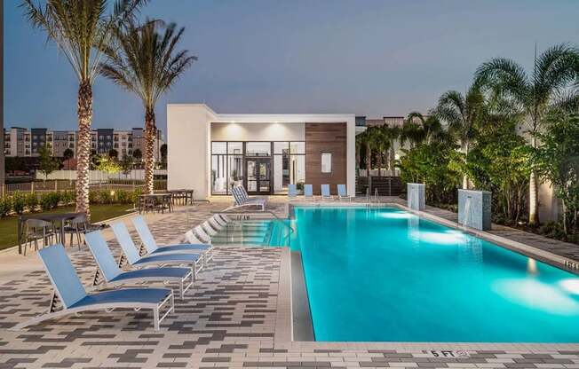 A swimming pool surrounded by lounge chairs and palm trees.