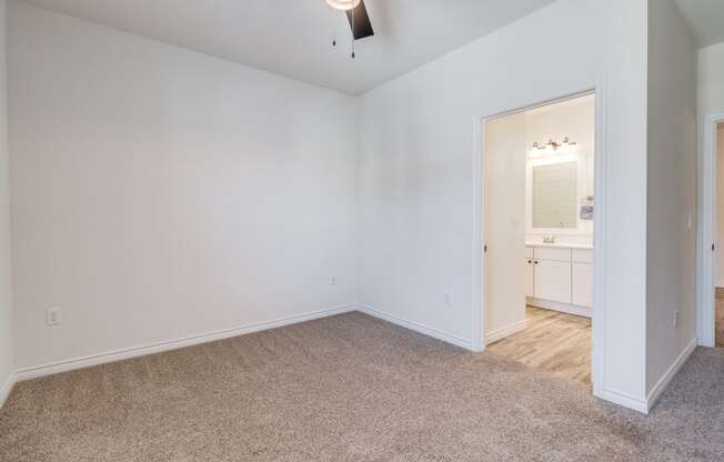 a bedroom with white walls and carpet and a door to a bathroom