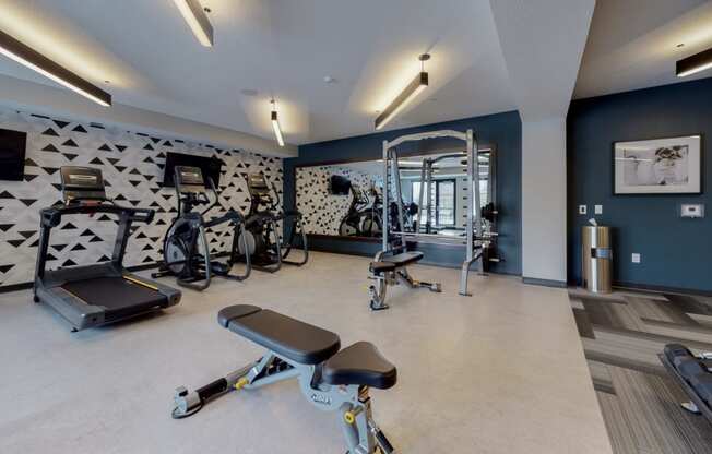 a gym with exercise equipment and a wall with a geometric pattern