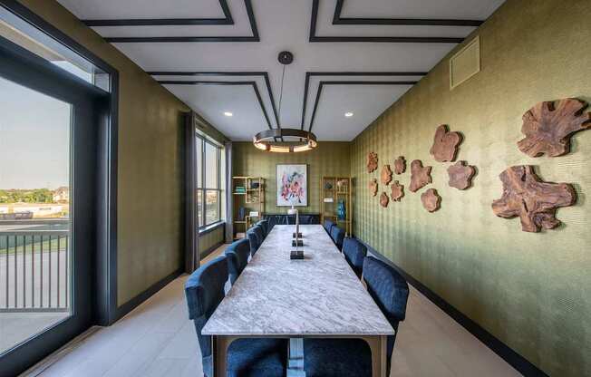 A long table with chairs and a wall with leaves on it.