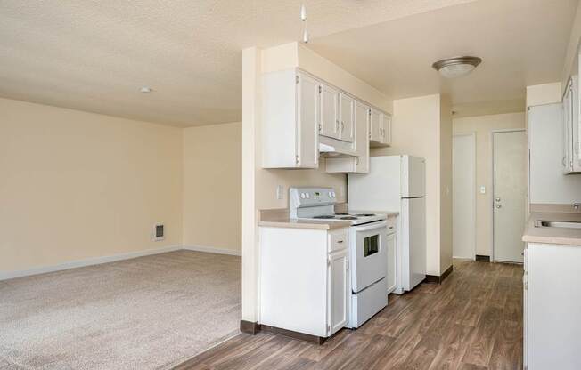 A kitchen with white appliances and wooden floors.