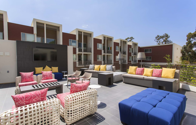 a patio with couches tables and chairs and apartments in the background