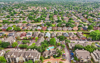 A bird's eye view of a suburban neighborhood with houses and a pool.