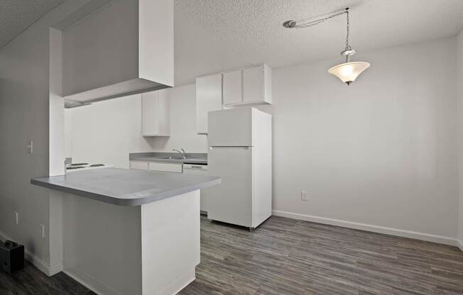A kitchen with white cabinets and a wooden floor.