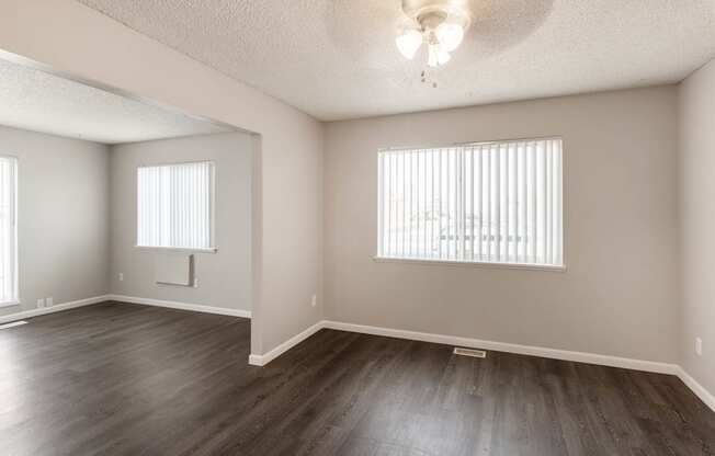 a bedroom with hardwood floors and two windows