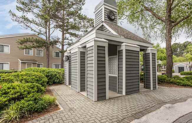 A small building with a clock tower sits in the middle of a brick walkway.