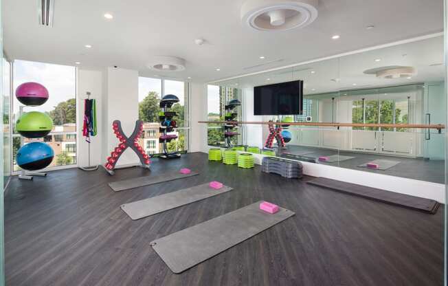 a yoga studio with yoga mats on the floor and a tv on the wall