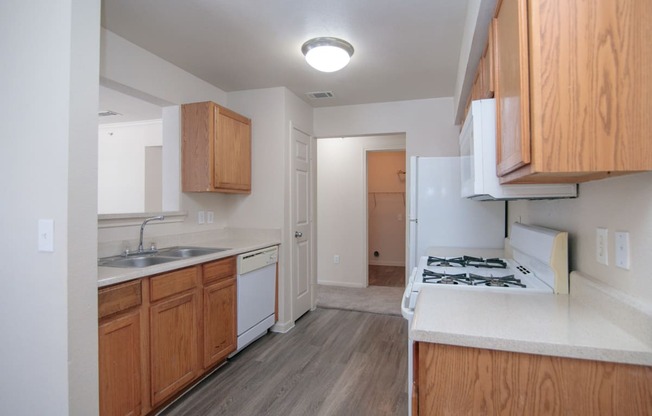 an empty kitchen with wooden cabinets and white appliances and a stove top oven