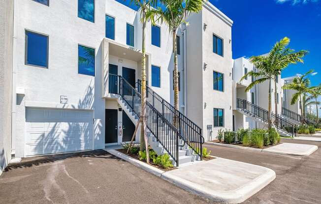 a large white building with stairs and palm trees at Altis Santa Barbara, Naples, FL