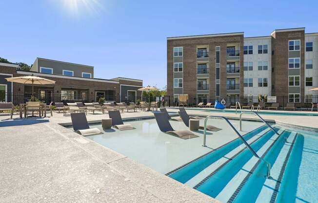 A sunny day at the pool with chairs and umbrellas.