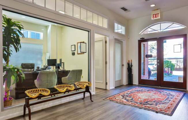 A leasing office with a bench, chairs, and a rug at The Inverness Apartments in Houston, TX