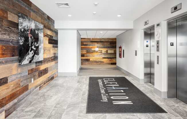 a hallway with elevators and a rug with a painting on the wall