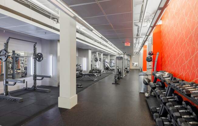 a gym with weights and a red wall and a row of pillars