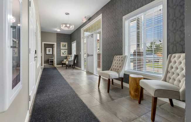 A hallway with a black carpet and white chairs.