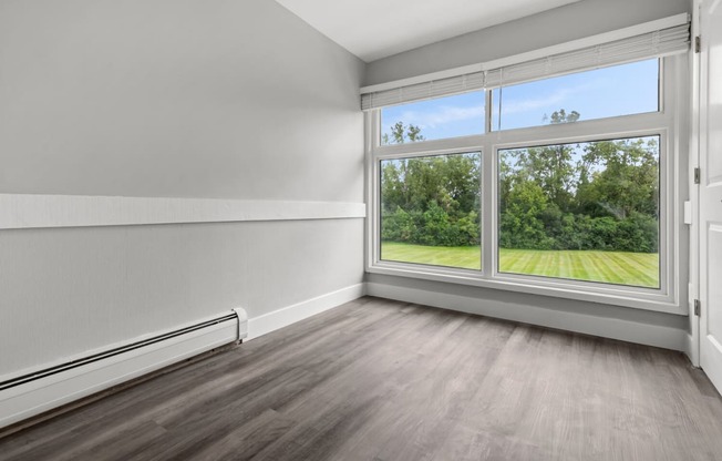 an empty room with a large window and wood floors