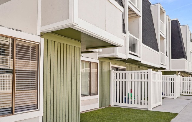 an exterior view of a row of apartments with grass and a sidewalk