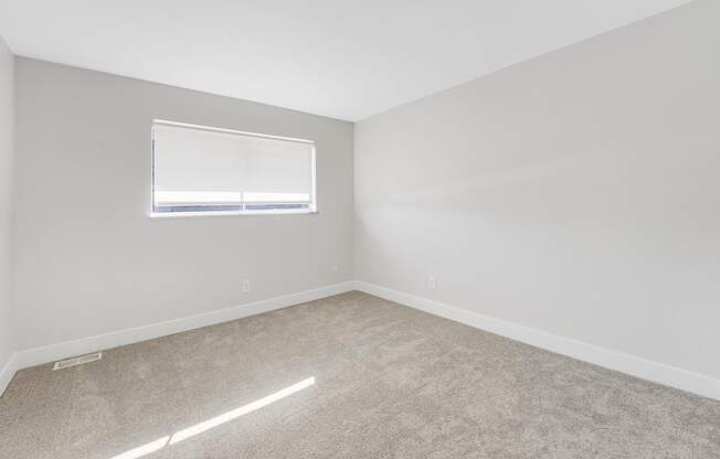 A room with a carpeted floor and a window.