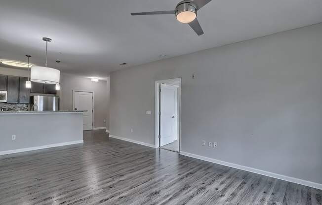an empty living room with a ceiling fan and a kitchen at Nexus at Sandhill, Columbia, SC 29229