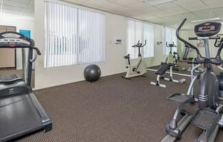 a gym with various exercise equipment on the floor and a window