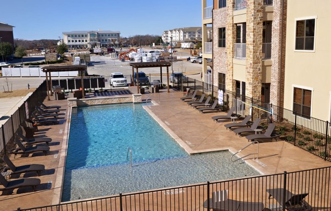 a swimming pool with lounge chairs in front of a building