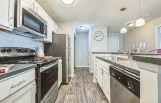 an open kitchen with stainless steel appliances and white cabinets