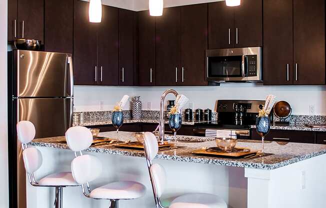 a kitchen with a bar and chairs and a stainless steel refrigerator