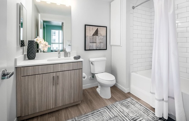 a bathroom with a toilet sink and shower and a mirror at OLiVE DTLA in Los Angeles, CA 90015