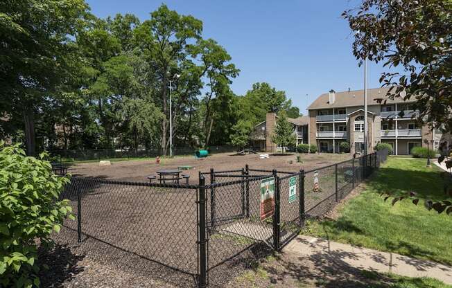 A black fence surrounds a playground with a sign on it.