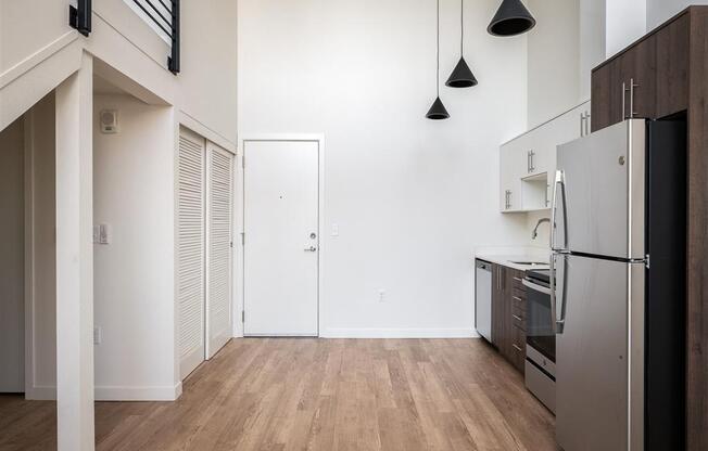 a renovated kitchen with white walls and wood floors and a stainless steel refrigerator