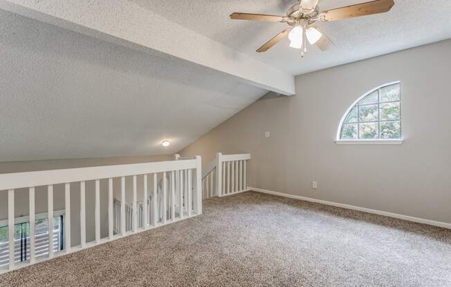 a large lofted bedroom with carpeted flooring and a ceiling fan