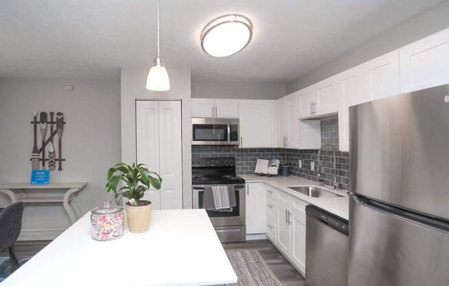 A kitchen with a white table and stainless steel appliances.