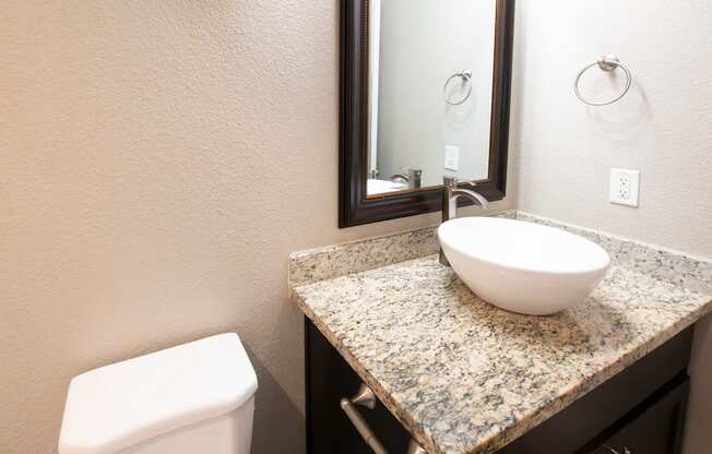 A bathroom with a granite countertop and a white toilet.