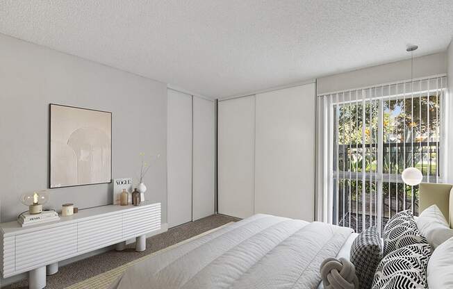 Model Bedroom with Carpet and Patio Accessibility at Madison Park Apartments located in Anaheim, CA.