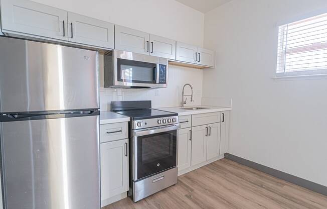 an empty kitchen with stainless steel appliances and white cabinets