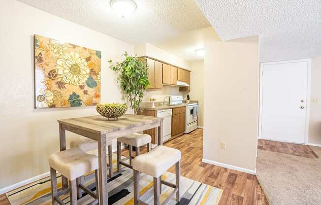 A dining area with a table and chairs and a painting on the wall.