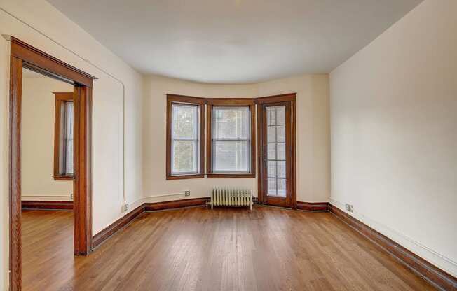 an empty living room with wood floors and a window