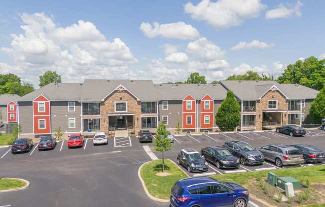 a parking lot in front of an apartment building with cars parked in front