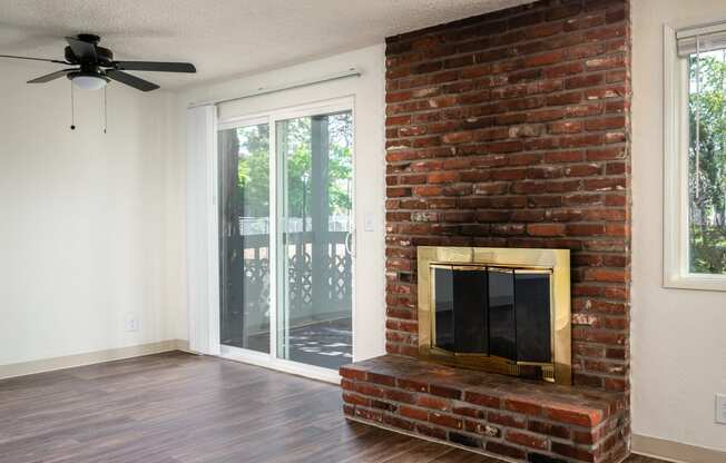 an empty living room with a brick fireplace and a sliding glass door