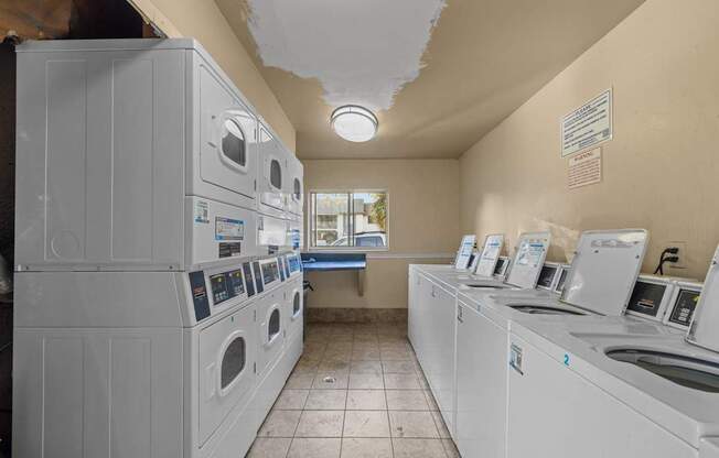 A laundromat with washers and dryers lined up.