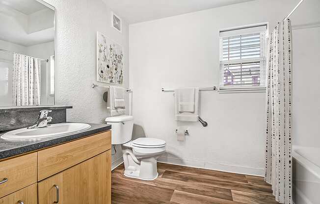 A bathroom with a toilet, sink, and a window at Lynbrook Apartments and Townhomes, Elkhorn, NE, 68022