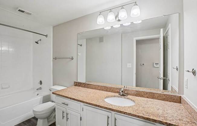 A bathroom with a granite countertop and a large mirror.